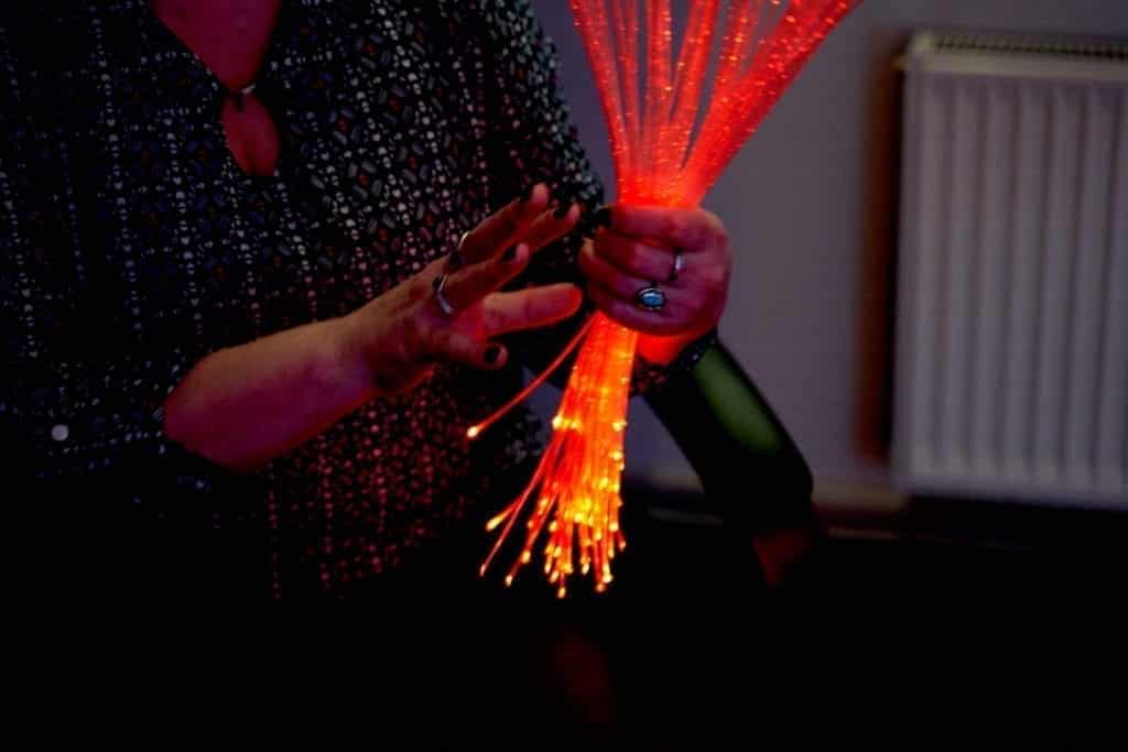 Woman in sensory room holding fiber optics